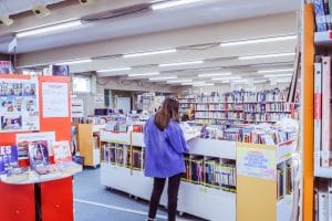 Fille qui lit devant une étagère dans une médiathèque