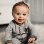 baby in gray sweater lying on white textile